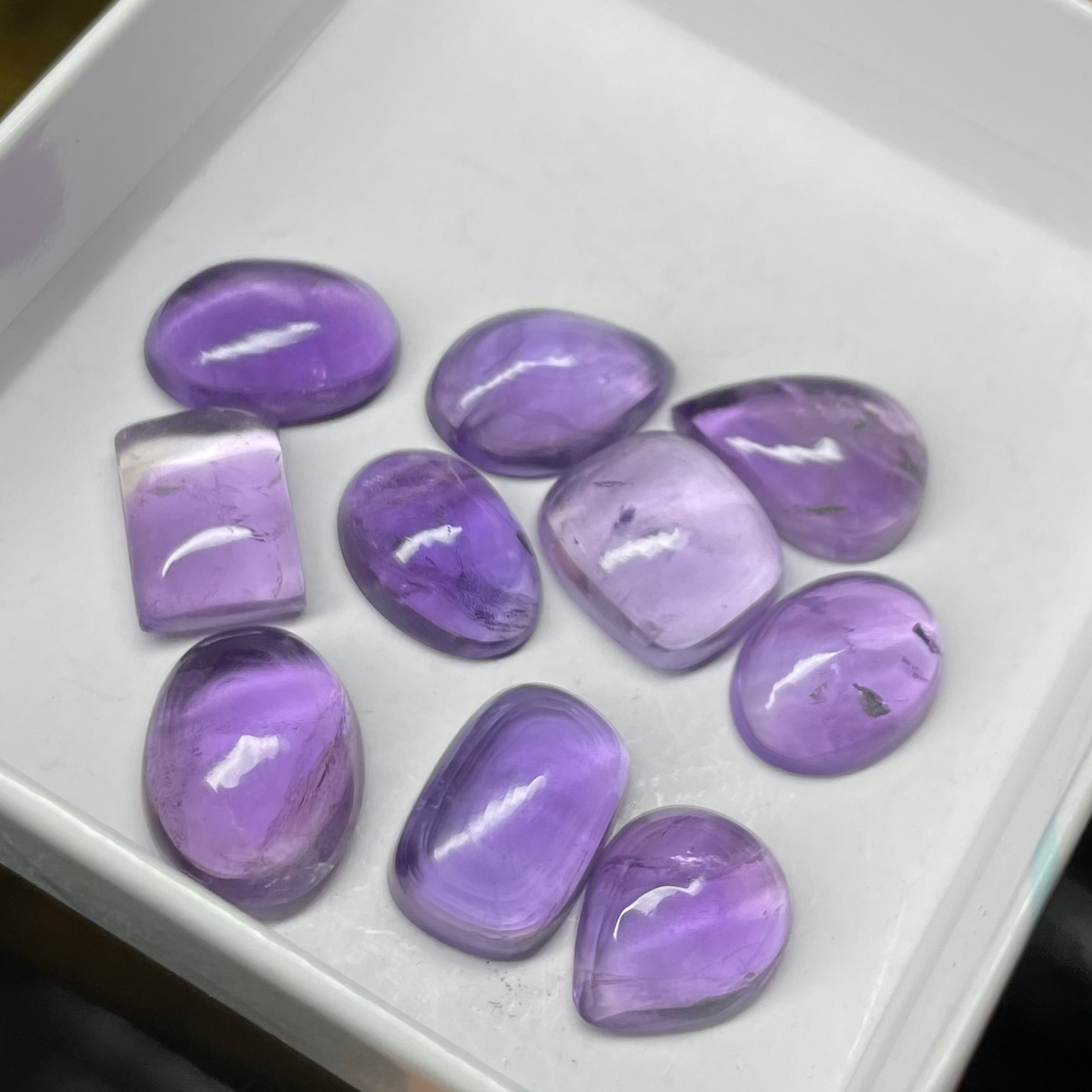 Purple gemstones in a white box held by a hand