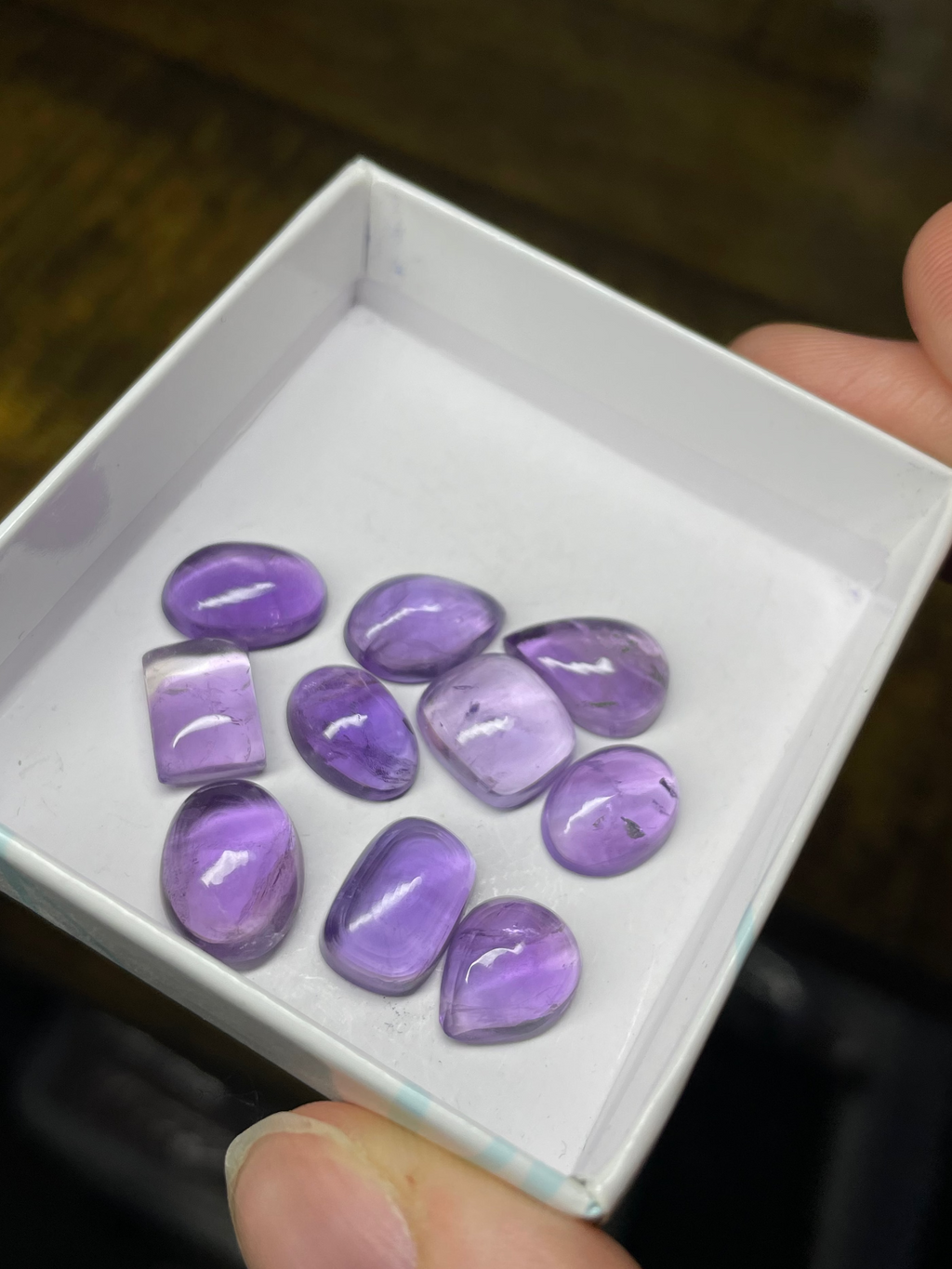 Box of purple gemstones held by a hand