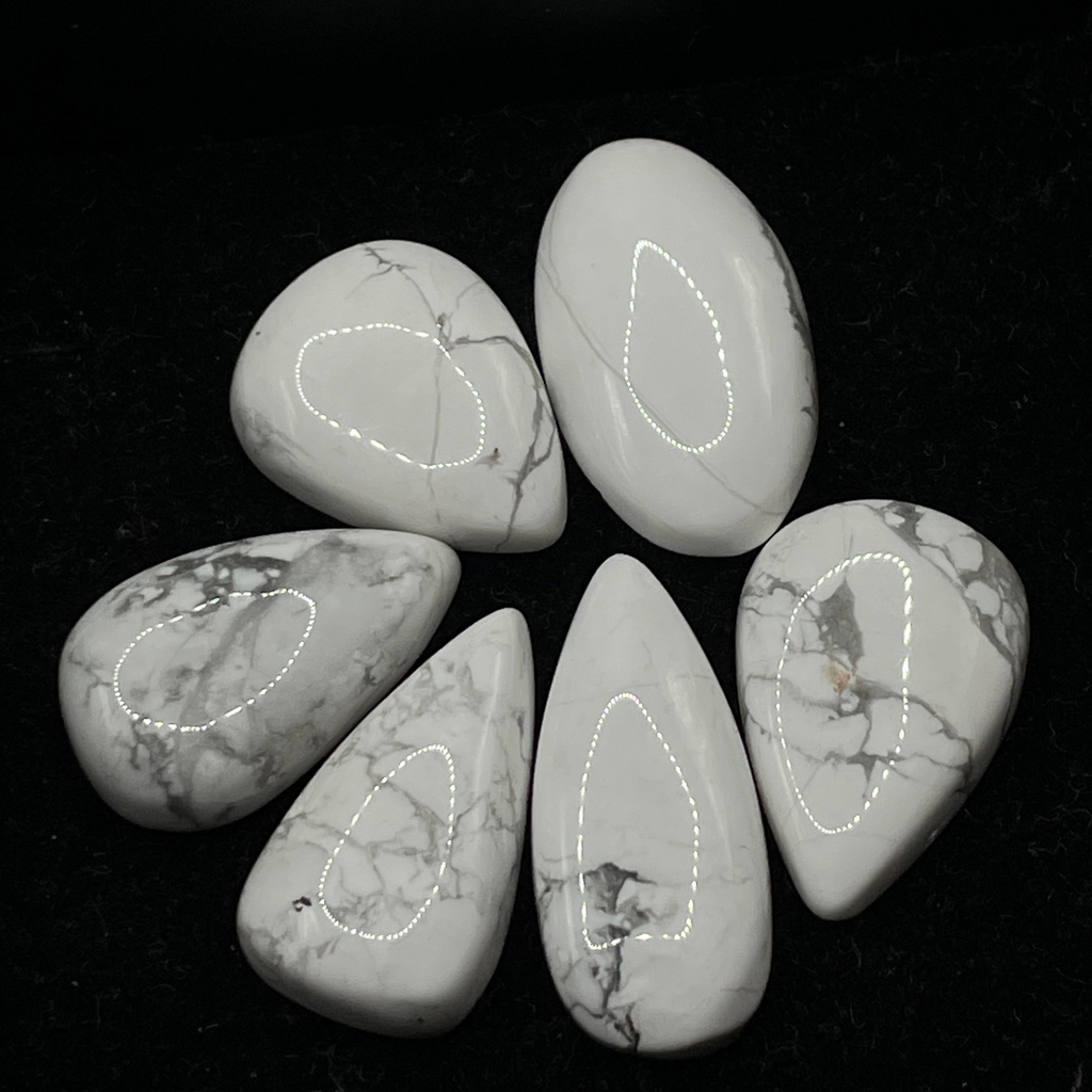 Five marbled stones with white and gray patterns on a black surface