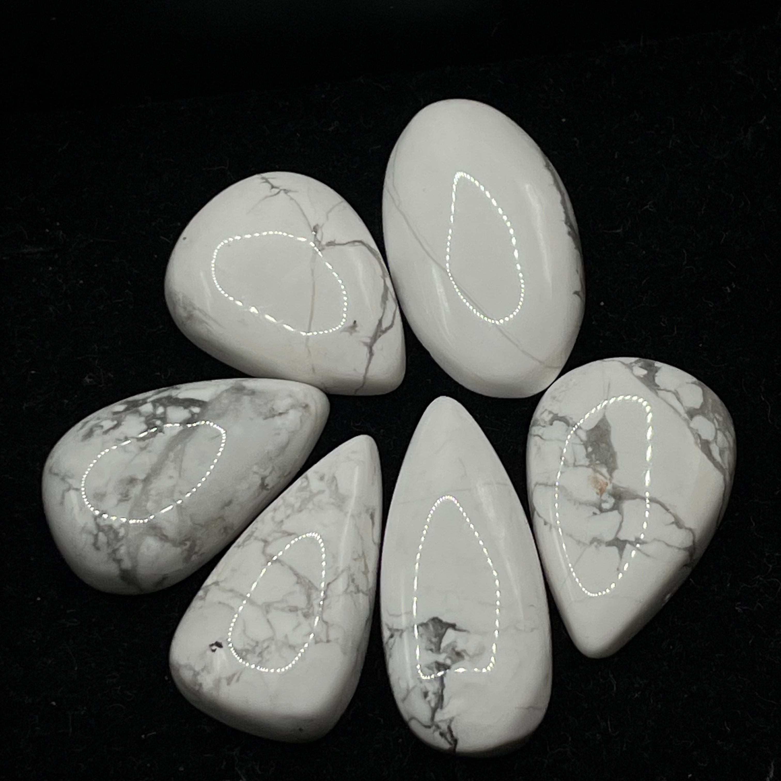 Five marbled stones with white and gray patterns on a black surface