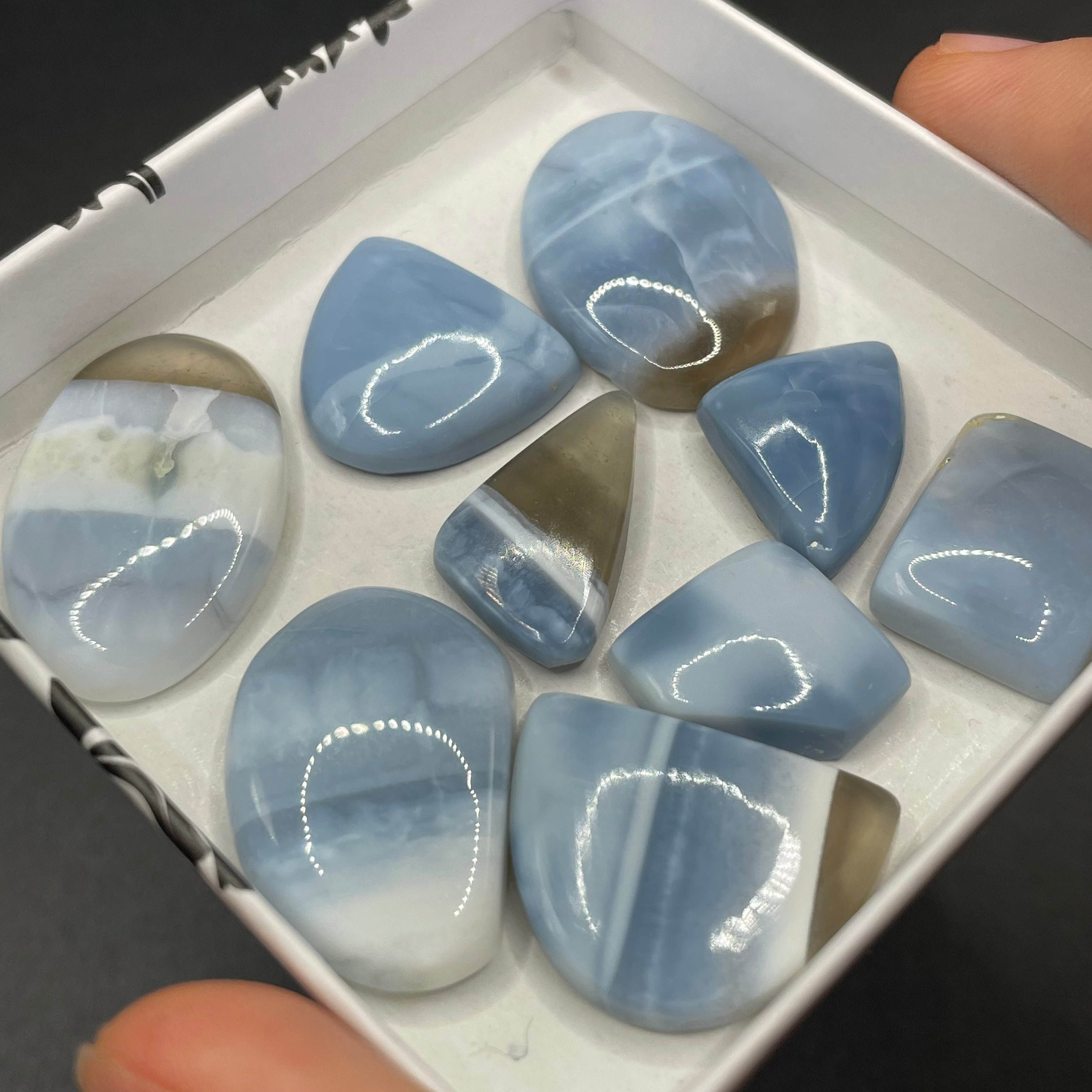 Box of blue stones with a hand holding it